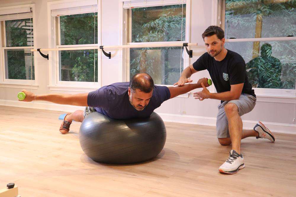 A Doctor of Physical Therapy coaching a core stabilization exercise on the stability ball