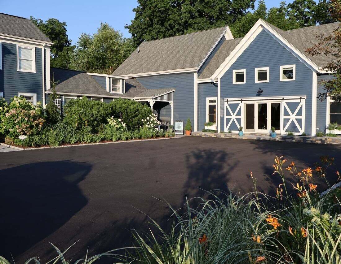 The blue barn-style clinic building at 10 Eliot Street with gardens and barn-door entrance