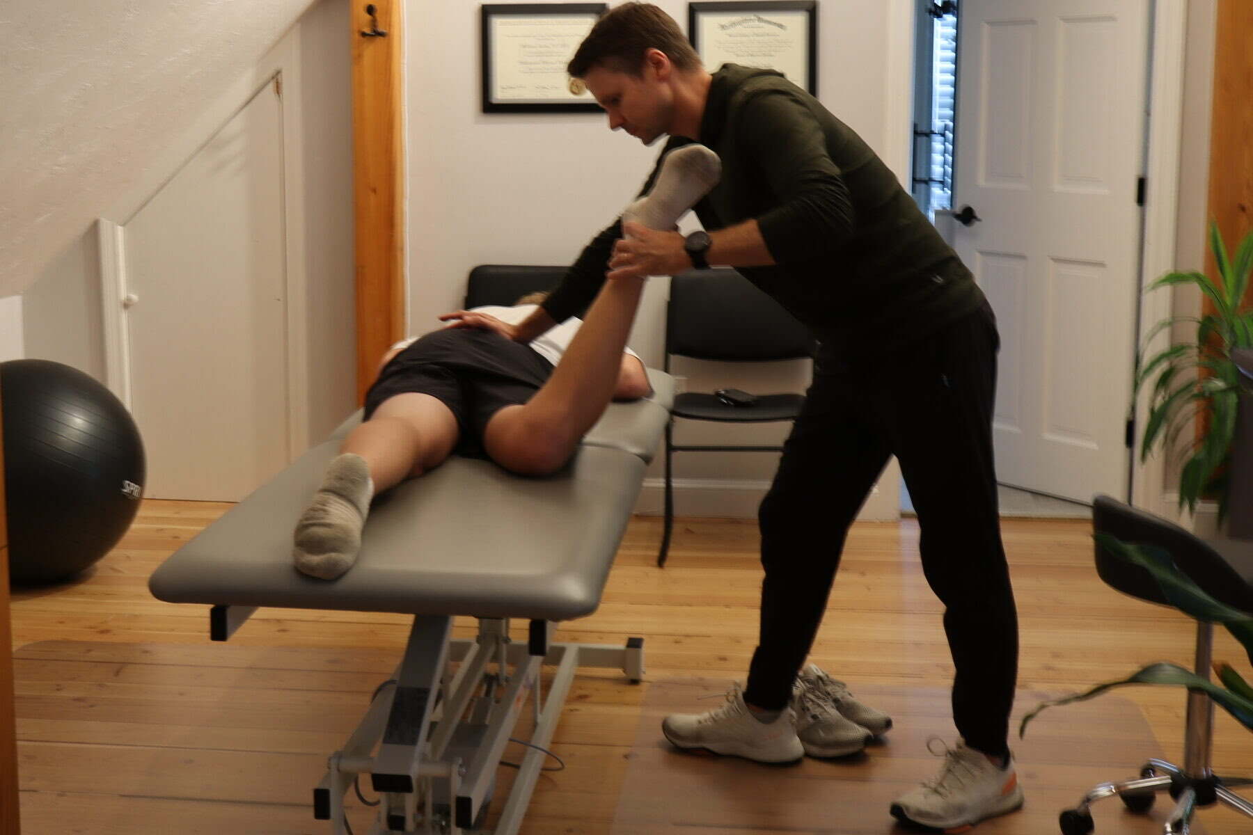 Dr. Shawn Sprague stretching a patient's hamstring on the treatment table at PT Progression
